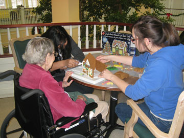 Intergenerational volunteers building a gingerbread house
